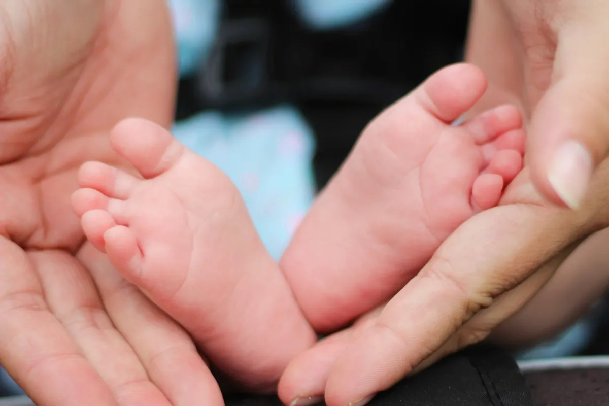 A newborn baby's feet cradled in a parent's hands